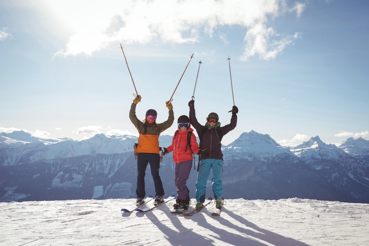 Celebrating skiers standing snow covered mountain