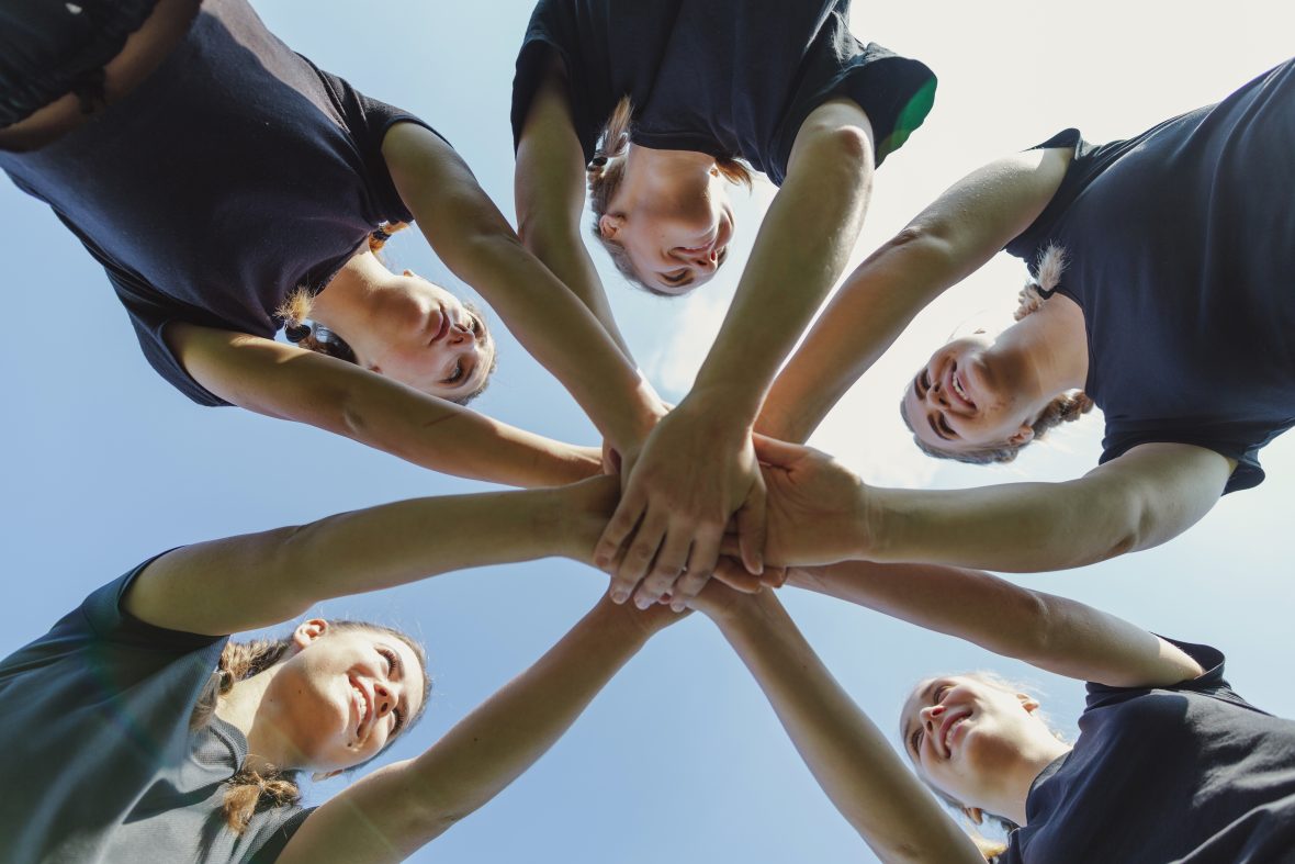 Smiling women putting hands together