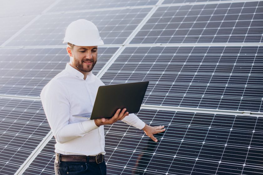 Young architect standing by solar panels making diagnostics computer